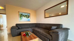 A modern living room with a sectional sofa, a wooden coffee table with flowers, a framed landscape painting, and a large mirror on the wall. - Apartment in Zaton (Zadar) with Terrace, Air condition, WIFI, Washing machine (4141-5) (Nin)