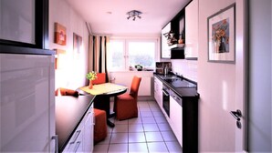 Une cuisine de taille réduite comprenant une table à manger, des chaises et un réfrigérateur.