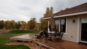 Terassi, jossa on ulkokalusteita, katettu patio ja näkymä puihin ja kukkuloille.