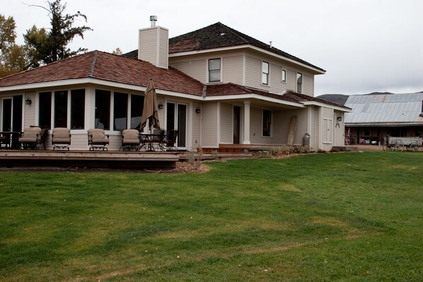 A two-story house with a covered patio area, a chimney, and a large lawn. - Single Family Home on 4 Eagle Ranch, Stunning Views of Mountain Vistas (Wolcott)
