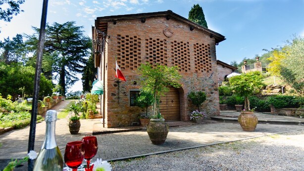 A rustic building with a brick facade and a wooden door, surrounded by potted plants and a gravel pathway. - Villa in Uzzano with 4 bedrooms sleeps 10 (Uzzano)