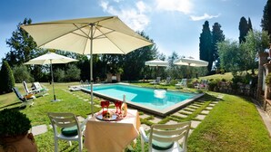 A poolside setting with a table, chairs, and umbrellas. - Villa in Uzzano with 4 bedrooms sleeps 10 (Uzzano)