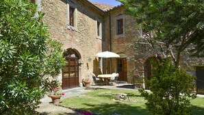 A stone building with a courtyard, a table with chairs, and potted plants. - Relax and peace in Cortona with Pool (Cortona)