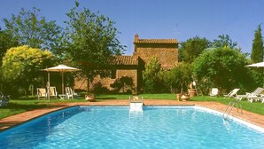 A rectangular swimming pool with clear blue water, surrounded by a brick building and lush greenery. - Relax and peace in Cortona with Pool (Cortona)