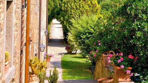 A stone building with a narrow pathway leading to a lush garden with various plants and flowers. - Relax and peace in Cortona with Pool (Cortona)
