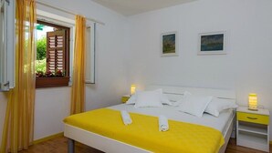 Un dormitorio con cama, cortinas, dos mesitas de noche y dos lámparas de pared.