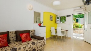 Un espacio habitable compacto con sofá, mesa de comedor, sillas y zona de cocina.