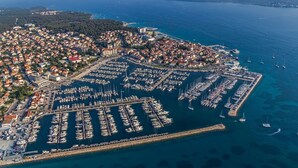 An aerial view of a coastal town with a marina filled with boats, surrounded by residential buildings and a clear view of the sea. - Apartment in Pakoštane with Terrace, WIFI (3539-4) (Pakoštane)