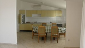 Une cuisine avec des meubles de couleur jaune, un pare-feu en carreaux et un coin repas comprenant une table et des chaises.