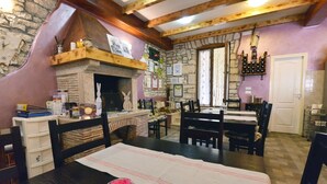 A cozy dining area with a stone fireplace, wooden beams, and a stone wall. - Holiday Home in Vodnjan with Terrace, Air condition, WIFI, Washing machine (3556-1) (Vodnjan)