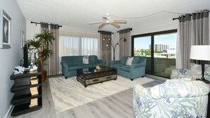 A living room with two sofas, a coffee table, a ceiling fan, and a large window with a view of buildings. - Steps to Siesta Key beach, restaurants and shops! (Sarasota)