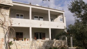 A two-story building with a stone facade, multiple balconies, and a small garden area with a table and chairs. - Apartment in Duće with Seaview, Terrace, Air condition, Washing machine (595-1) (Duce)