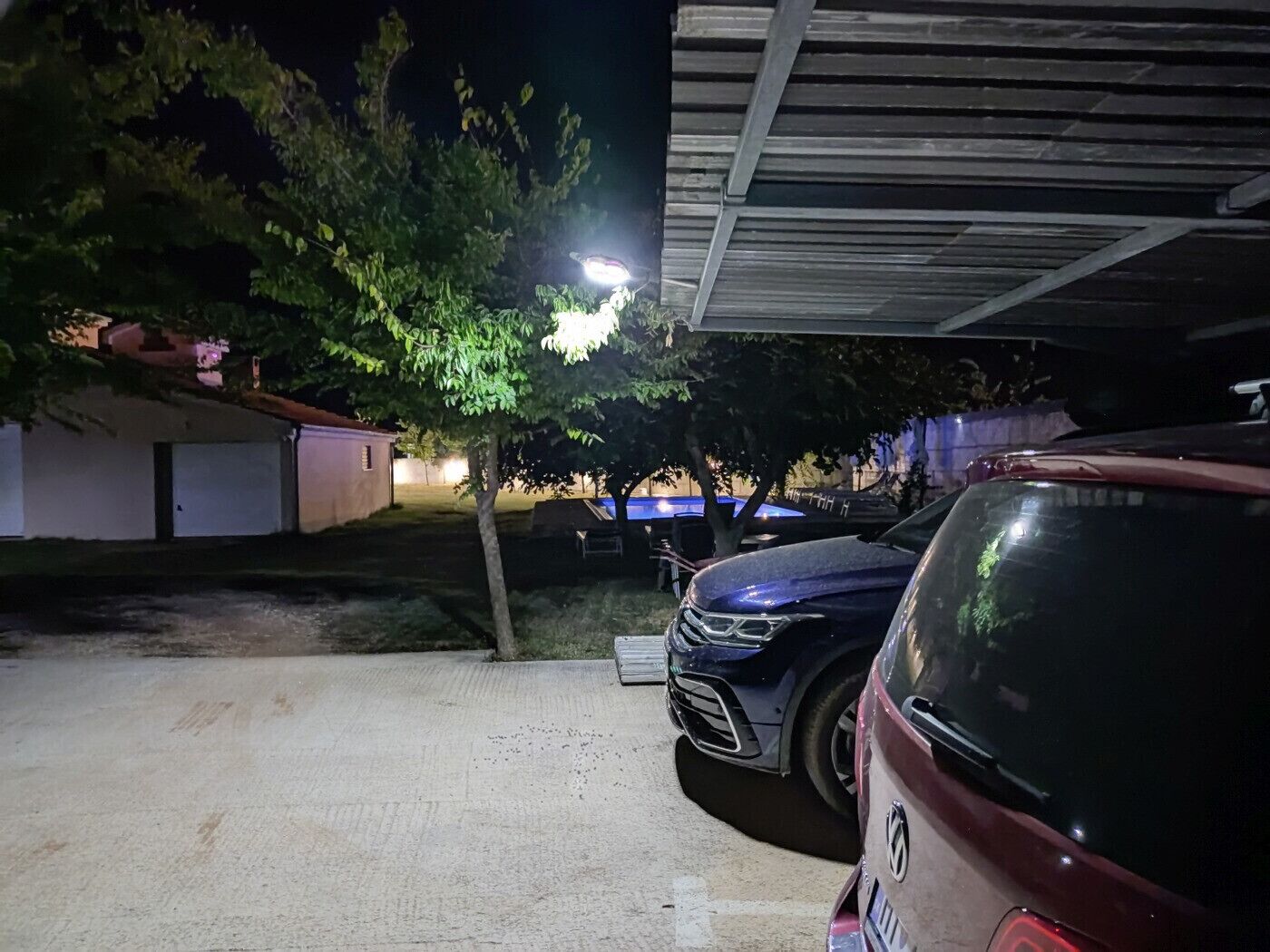 A parking area with a tree and a building in the background.