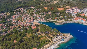 An aerial view of a coastal town with residential buildings, a marina, and a rocky coastline.