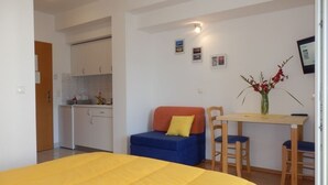 A bedroom with a bed, a small sofa, a dining table with chairs, and a kitchenette in the background. - Studio apartment in Duće with Seaview, Balcony, Air condition, WIFI (4173-7) (Duce)