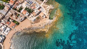 Vue aérienne d’une ville côtière avec ses bâtiments, sa plage et ses eaux turquoise cristallines.