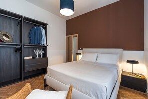 Ein Schlafzimmer mit Bett, Kleiderschrank, Spiegel und Nachttisch mit Lampe.