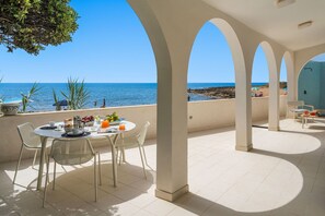 Eine Terrasse mit Frühstückstisch mit Blick auf das Meer.