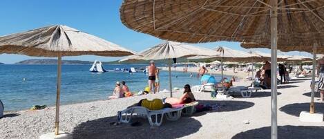 Una playa con sombrillas y gente tomando el sol.