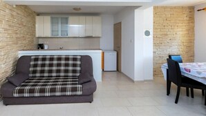 A compact living space with a sofa, a dining table, and a kitchenette. - Apartment in Lopar with Balcony, Air condition, WIFI (4421-1) (Lopar)