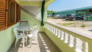 A balcony with a table and chairs, a staircase, and a view of parked cars. - Apartment in Lopar with Balcony, Air condition, WIFI (4421-1) (Lopar)