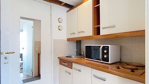 Una cocina compacta con armarios blancos, un microondas y una encimera de madera.