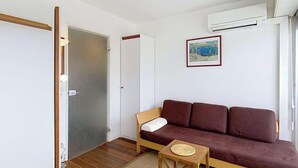 Una habitación con un sofá marrón, una pequeña mesa de madera y una puerta que da a otra habitación.