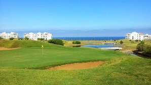 Campo de golf con búnkeres, una bandera y un obstáculo acuático.
