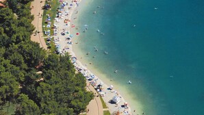 An aerial view of a beach with a curved shoreline, surrounded by dense greenery and a few buildings. - Apartment in Bašanija with Terrace, Air condition, WIFI, Dishwasher (113-4) (Bašanija)