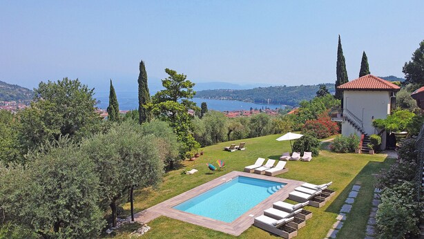 Zona de piscina con sillones y vista al mar.