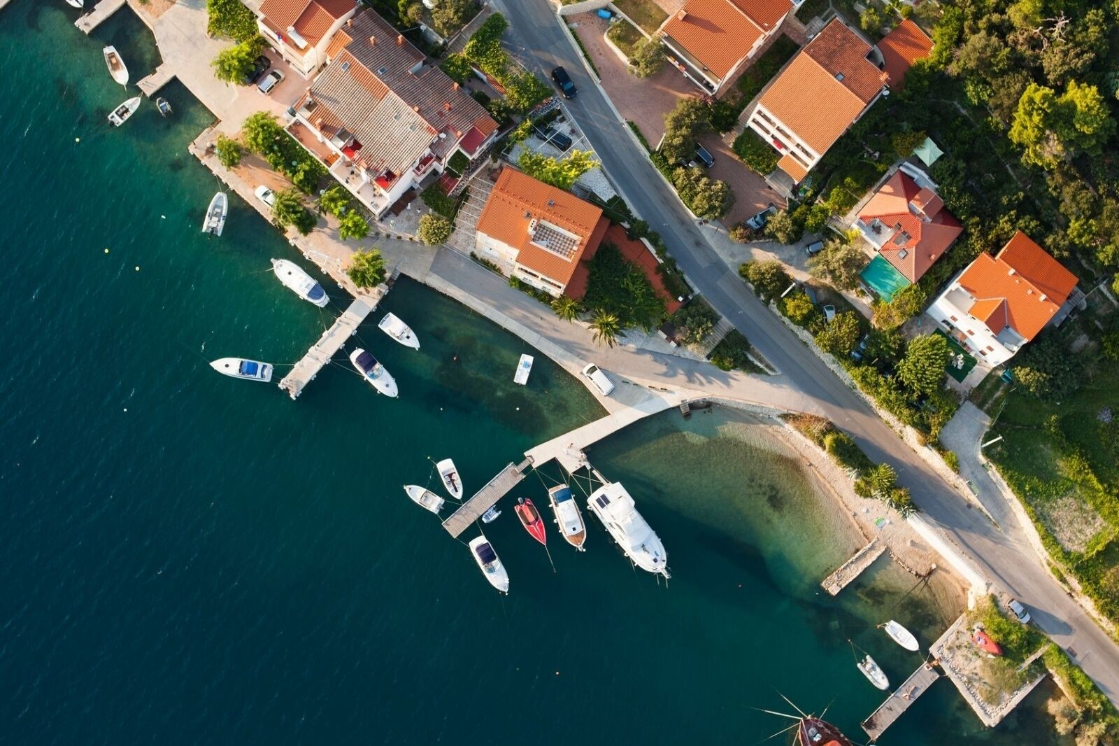 An aerial view of a coastal area with houses, a marina, and boats.