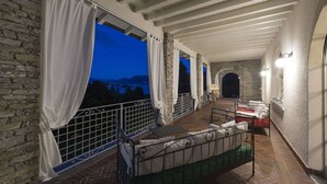 Ein Balkon mit einem Bett, einer Steinmauer und Blick auf eine Brücke im Abenddämmerung.