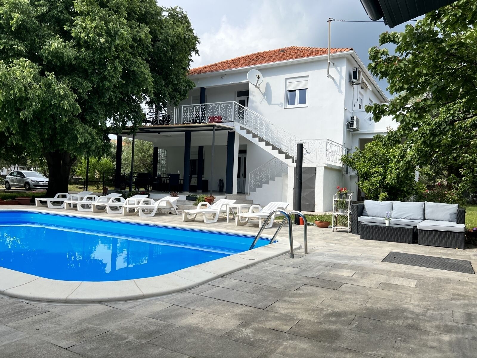 A two-story house with a swimming pool, outdoor seating, and a covered patio.