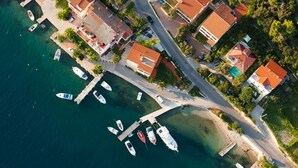 Vue aérienne d’une zone côtière avec des maisons, un port de plaisance et des bateaux.