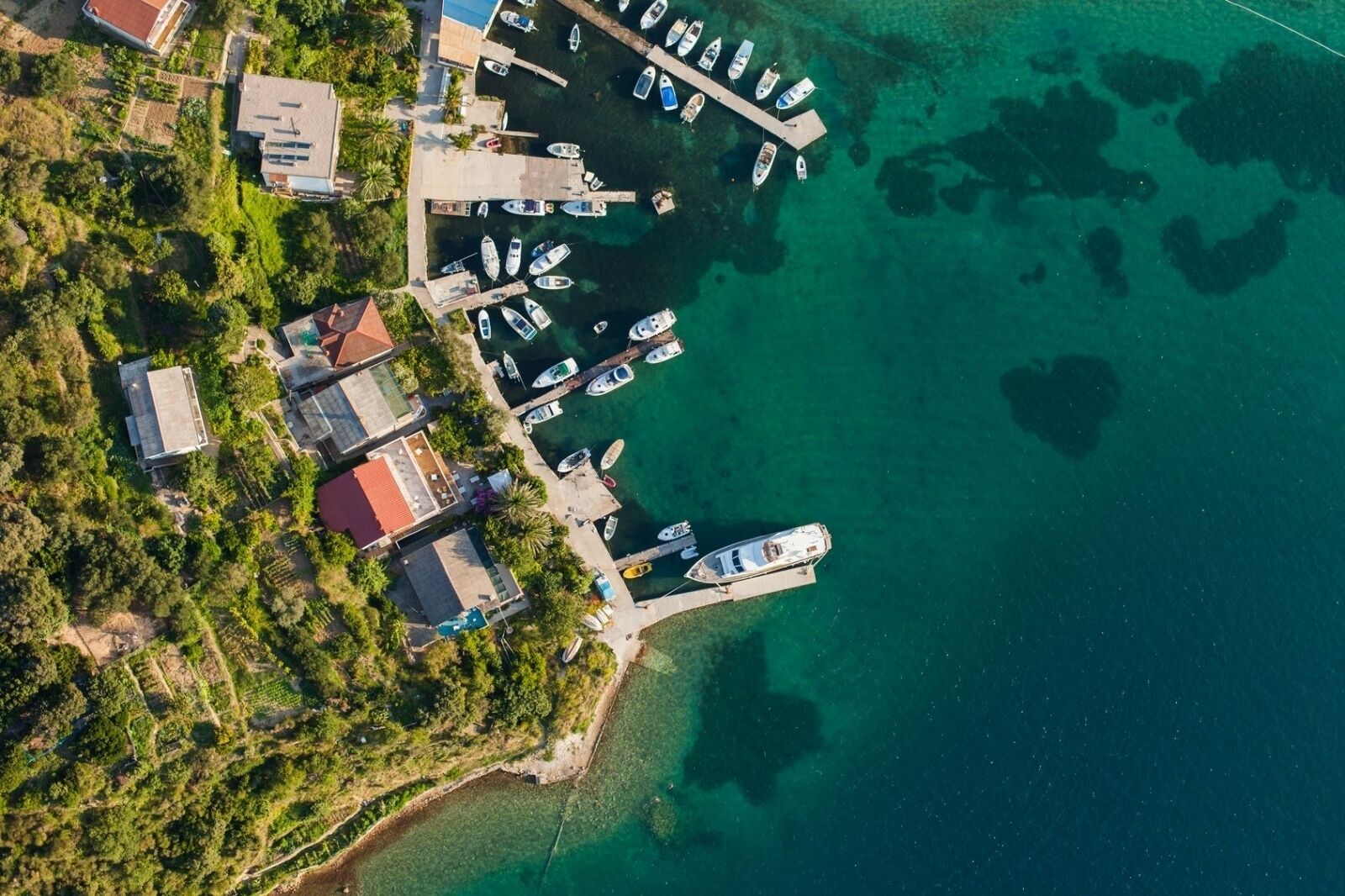An aerial view of a coastal area with a marina, boats, and residential buildings.