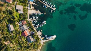 Vue aérienne d’une zone côtière avec un port de plaisance, des bateaux et des immeubles résidentiels.
