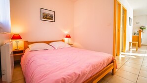 Een slaapkamer met een bed, twee bedlampen, een nachtkastje, een foto aan de muur en een deur naar een badkamer.
