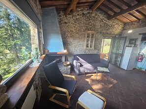 Ein rustikaler Innenraum mit Steinwänden, einem Kamin, einer Couch und einem Essbereich.