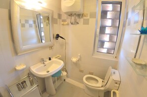 Une salle de bain avec un lavabo, des toilettes et une fenêtre.