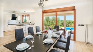 A modern kitchen with a dining area, large windows, and a view of a pool. - Holiday Home in Buje with Terrace, Air condition, WIFI, Washing machine (3356-1) (Buje)