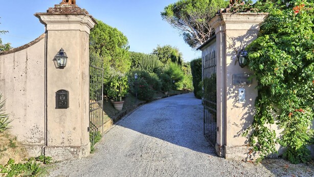 A gravel driveway leading to a gated entrance with statues on top, surrounded by lush greenery. - Villa in San Concordio Di Moriano with 6 bedrooms sleeps 12 (Lucca)