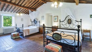 A bedroom with a wooden ceiling, two beds, a window with a view of greenery, and a radiator. - Villa in San Concordio Di Moriano with 6 bedrooms sleeps 12 (Lucca)