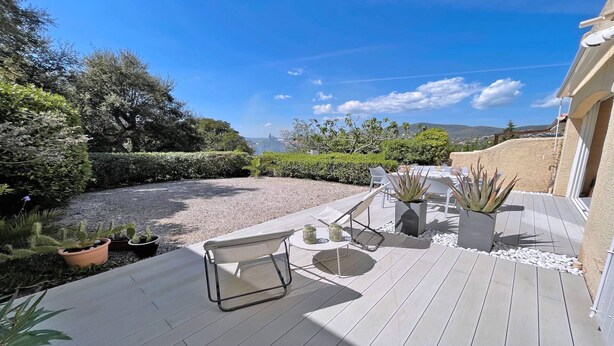 Une terrasse aménagée avec du mobilier d’extérieur, des plantes en pot et une vue sur le paysage.