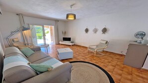 Un salon avec un canapé, un téléviseur, un fauteuil et une petite table.