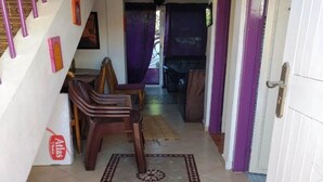 A hallway with a staircase, a dining area with chairs, and a door with a purple curtain.