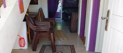 A hallway with a staircase, a dining area with chairs, and a door with a purple curtain.