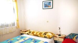 Un dormitorio con cama, mesita de noche, lámpara y ventana con cortinas.