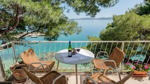 A balcony with wicker chairs, a table with a bottle and glass, and a view of the sea and mountains. - Apartment in Pisak with Seaview, Terrace, Air condition, WIFI (196-1) (Pisak)