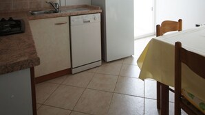 Una cucina compatta con forno a microonde, frigorifero, lavello e zona pranzo con tavolo e sedie.