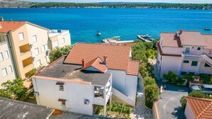 A coastal residential area with buildings featuring red-tiled roofs and a clear view of the sea. - Apartment in Barbat with Balcony, Air condition (660-3) (Rab)